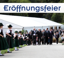 Eröffnungsfeier im Zelt Bayern: Gala-Referenz Hohenschwangau Großes weißes VIP-Zelte mit prominenten Gästen davor und jungen Trachtlerinnen, die Spalier stehen.